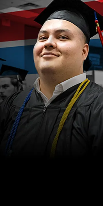 UTI trade school graduate wearing a black cap and gown with honor cords, smiling at commencement ceremony.