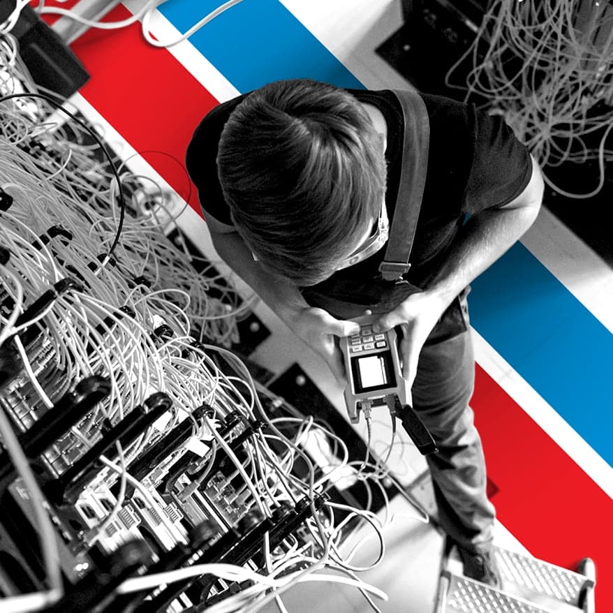 UTI trade school graduate wearing a black cap and gown with honor cords, smiling at commencement ceremony.