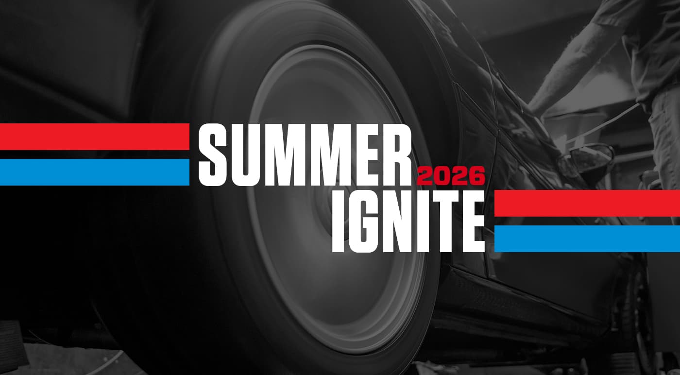 UTI trade school graduate wearing a black cap and gown with honor cords, smiling at commencement ceremony.